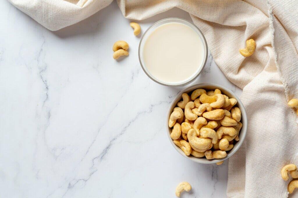 vegan cashew milk glass with cashews nuts marble background