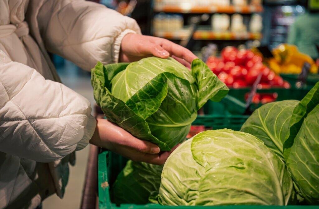 woman chooses cabbage grocery store closeup